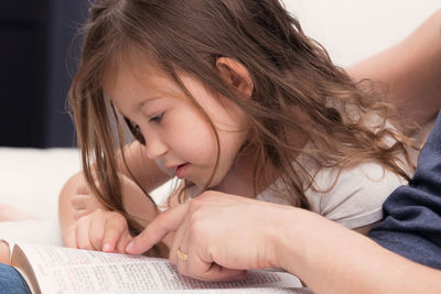 Close-up portrait of a girl with book on bed