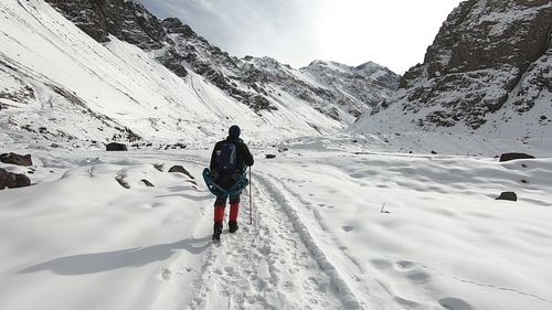 Rear view of man walking on snowcapped mountain