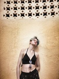 Fashionable woman standing against wall