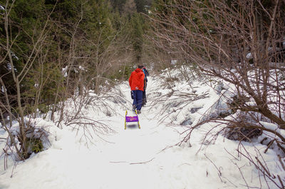 Full length of person on snow covered tree during winter