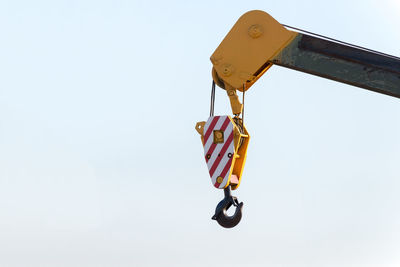 Low angle view of crane hanging against clear sky