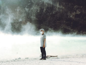 Full length of young man standing on land by hot spring