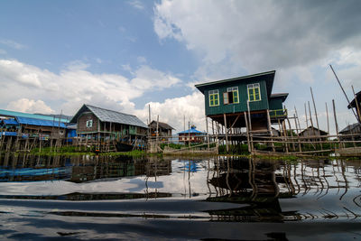 Built structure by lake and buildings against sky