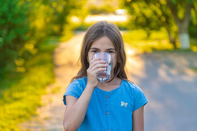 Portrait of girl drinking water at park