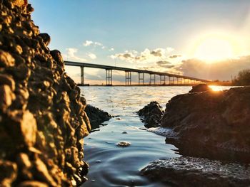 Bridge over sea against sky during sunset