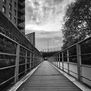 Footbridge over footpath amidst buildings in city