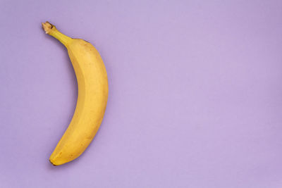 Banana on purple background. top view with copy space