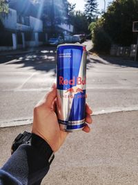 Close-up of hand holding drink on road