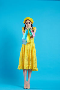 Portrait of woman standing against blue background