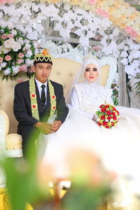 Midsection of man and woman holding flower bouquet