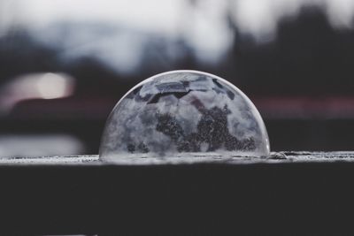 Close-up of crystal ball on glass against sky