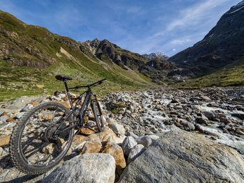 Bicycle parked on rock against sky