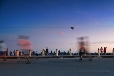 Blurred motion of men running on road against blue sky