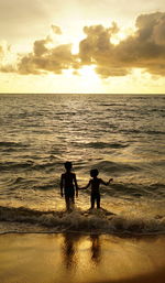 Silhouette people on beach against sky during sunset