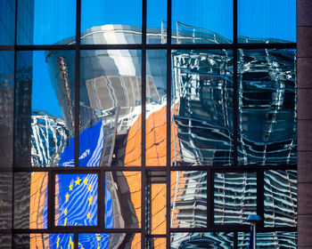 Low angle view of glass building against blue sky