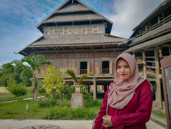 Portrait of woman standing against building