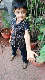 High angle view of boy showing henna tattoo on hand by potted plants