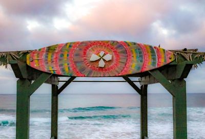 Multi colored umbrella by sea against sky