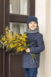 A  boy  in spring coats with a bouquet of acacia