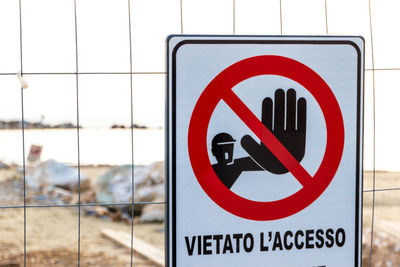 Close-up of warning sign with text on fence