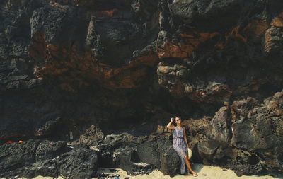 Rear view of woman standing on rock in cave