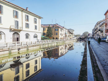 Reflection of buildings in canal against sky