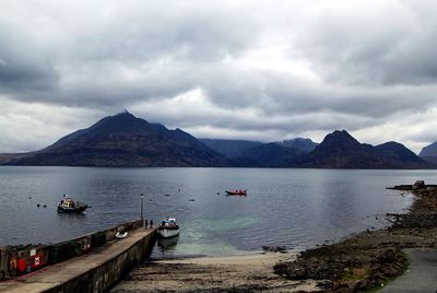 Boats in sea against cloudy sky