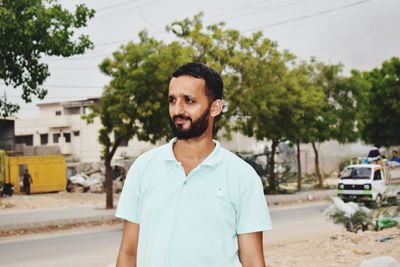 Portrait of young man standing against trees