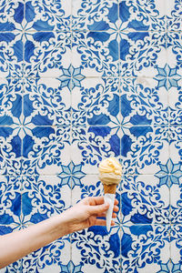 Hand holding ice cream cone against wall covered with portuguese tiles
