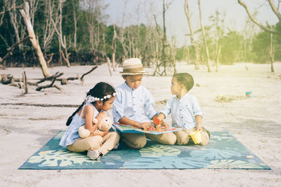 Happy siblings sitting on picnic blanket