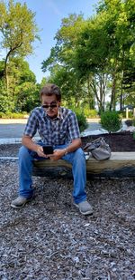 Portrait of man using mobile phone while sitting outdoors