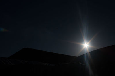 Low angle view of illuminated sun in sky