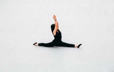 Full length of woman doing yoga against white background