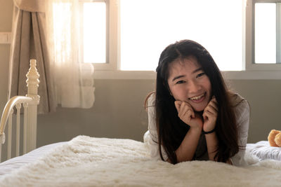 Portrait of smiling young woman lying on bed