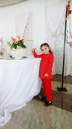 Full length portrait of girl standing against red wall