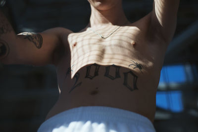 Midsection of shirtless man with tattoo