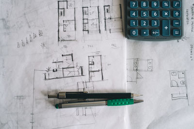 Close-up of blueprint with calculator and writing instrument