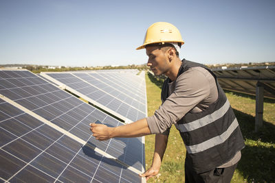 Young male engineer photographing solar panels through smart phone at power station