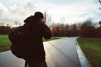 Rear view of man standing on road against sky