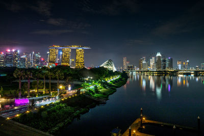 Illuminated modern buildings in city against sky at night