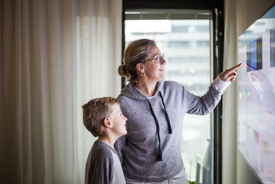 Mother guiding son in using smart tv at home