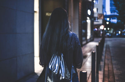 Rear view of woman standing by building in city