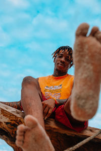 Low angle view of man sitting against sky