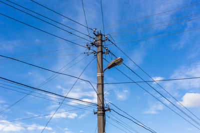 Low angle view of electricity pylon against blue sky