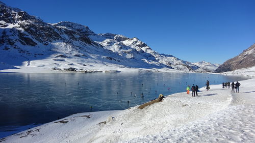 People on snowcapped mountain against clear sky