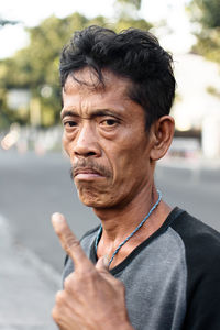 Portrait of man pointing against trees