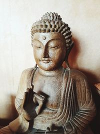 Close-up of buddha statue against wall