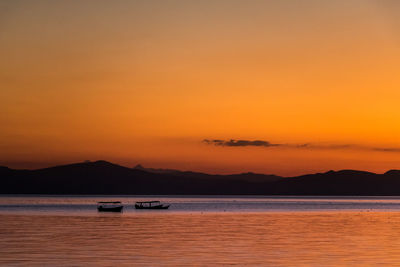 Silhouette of boats in sea during sunset