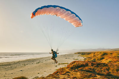 Young man paragliding during sunset in baja, mexico.