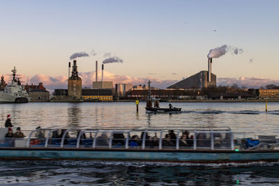 Boats in river against sky in city